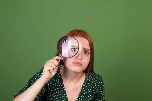 GGD-inspectrice kijkt door een vergrootglas – Bezwaar GGD inspectie kinderopvang indienen? Niet eens met GGD inspectie? Ontdek je juridische opties.
